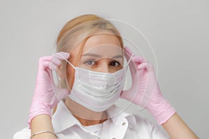 The doctor puts on a mask. Close-up portrait of medical staff. A woman in a protective mask .Isolated on a white