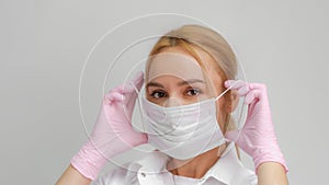 The doctor puts on a mask. Close-up portrait of medical staff. A woman in a protective mask .Isolated on a white