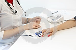 The doctor puts on the sensor measuring the pulse and oxygen in the blood on the patient`s finger