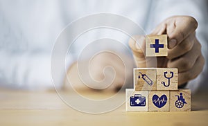 Doctor putting healthcares icon which print screen on stacking wooden cube for health medical insurance concept