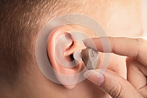 Doctor putting hearing aid in patient`s ear