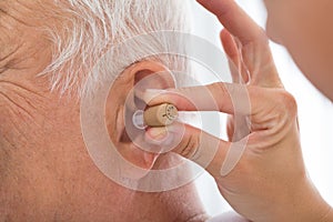 Doctor Putting Hearing Aid In Patient`s Ear