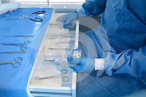 Doctor putting medical forceps into drawer, closeup. Table with different surgical instruments