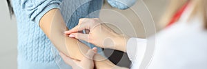 Doctor putting patch on patients forearm in clinic closeup