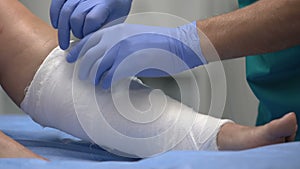 Doctor putting roller bandage on patient leg, medical treatment in hospital