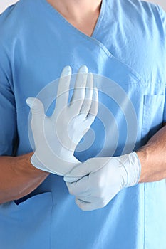 Doctor putting on sterile gloves isolated white