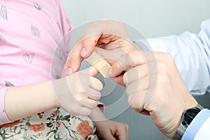 Doctor putting to girl plaster on the sore finger