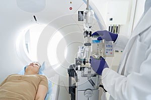 Doctor radiologist controls MRI or CT or PET Scan with female patient undergoing procedure