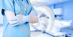 Doctor radiologist in a medical uniform against the background of an MRI computer tomograph in the office. Soft blurred toned