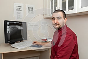 A doctor radiologist at the workplace looks at images from an X-ray machine on a computer monitor