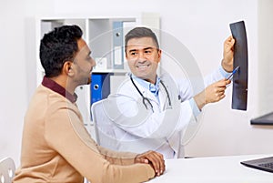 Doctor with x-ray and male patient at clinic