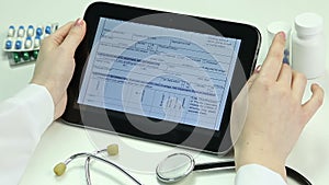 Doctor reading health insurance agreement on tablet. Electronic medical records