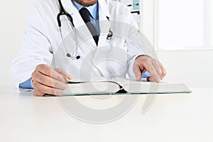 Doctor reading a Medical Book in Office Desktop. Health care,