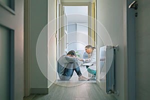 Doctor reassuring and helping to patient sitting on room floor