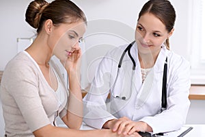 Doctor reassuring her female patient while sitting at the desk. Medicine, help and health care concept