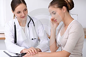 Doctor reassuring her female patient while sitting at the desk. Medicine, help and health care concept