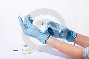 Doctor, researcher holds hands syringe in blue glove holding flu, measles, rubella or hv vaccine and syringe with needle