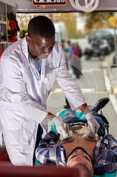 Doctor resuscitating patient with help of defibrillator