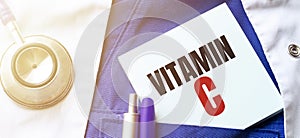 Doctor robe, stethoscope, pens and note with text VITAMIN C