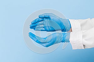 Doctor`s hand in a blue medical glove holds an object on a blue background. infection control. mocap, you can insert your product