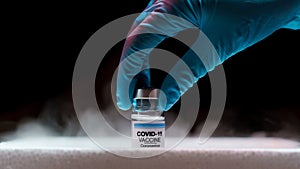 Doctor`s hand holding bottle vaccine Covid-19 from storage box. Medication treatment concept