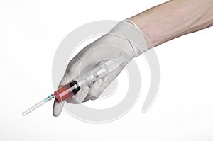 Doctor's hand holding a syringe, white gloved hand, a large syringe, the doctor makes an injection, white background