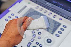 Doctor`s hand holding ultrasound probe of ultrasound scanner for medical diagnostics