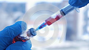 Doctor`s hand holds a syringe and a red vaccine bottle at the hospital. Health and medical concepts.