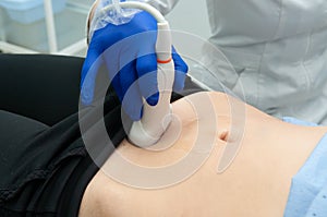 Doctor`s hand moves ultrasound sensor on pregnant woman`s stomach in hospital photo