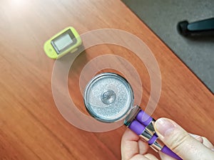 Doctor`s hand with a phonendoscope membrane over a wooden table close up