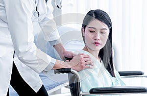 The doctor`s hand rests on the shoulder of the female patient Which sat in a wheelchair to encourage And give patients