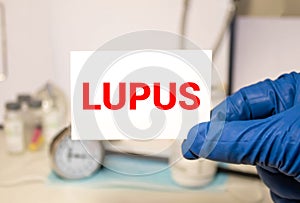 Doctor's hands in blue gloves shows the word lupus. Medical concept