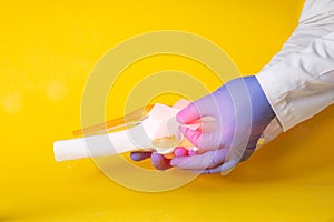 Doctor`s hands gluing a medical plaster on a model of a sore knee joint, yellow background. Knee pain concept, synovitis and photo
