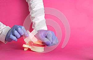 The doctor`s hands are gluing a medical plaster on the released nucleus pulposus, intervertebral hernia, pink background. photo