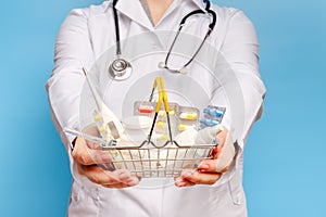 Doctor`s hands are holding shopping cart with various pills and tablets