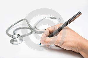 Doctor's hands with a plane-table, pen and stethoscope on white table