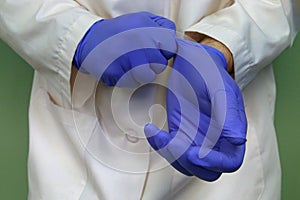 Doctor`s Hands Putting on Blue Nitrile Rubber Gloves Up Close