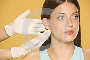 Doctor`s hands touching the ear of a young woman