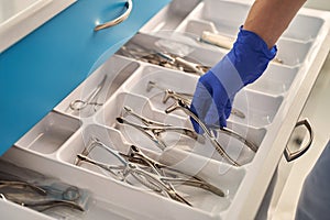 Doctor's hands wearing a disposable medical gloves holding a stainless steel nasal speculum for ENT examination over