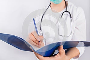 Doctor`s hands in a white coat hold a folder and fill out a medical document close-up isolated on a white background.