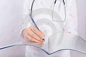 Doctor`s hands in a white coat hold a folder and fill out a medical document close-up isolated on a white background.