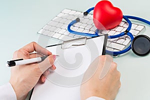 Doctor`s hands in a white medical coat write a prescription, white keyboard and red heart on a blue background. concept of