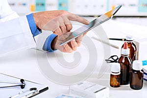 Doctor`s hands working on a digital tablet at his Office photo