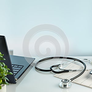 Doctor's office desk with laptop, cardiogram, and stethoscope with copy space