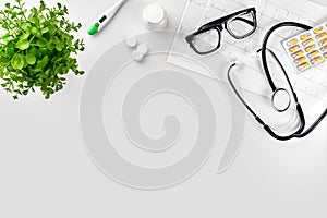 Doctor`s office desk with medical documents, charts, eyeglasses and stethoscope. Top view. Copy space