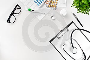 Doctor`s office desk with medical documents, charts, eyeglasses and stethoscope. Top view. Copy space