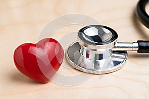 Doctor`s stethoscope with shinny red heart on wooden table, health care, medical exam or cardiology concept