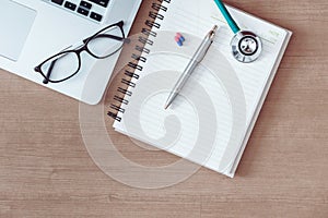 Doctor`s table desktop workspace with stethoscope and personal laptop.