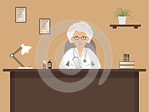 Doctor`s workplace. An elderly female doctor is sitting at the desk