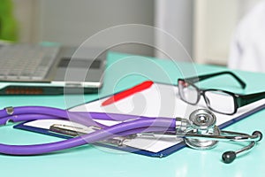 Doctor`s workspace working table with patient`s discharge blank paper form, medical prescription, stethoscope on desk